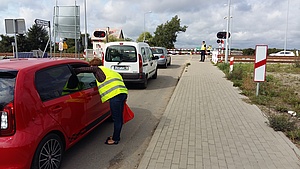 Samochody przed zamkniętym przejazdem. Kierowcy otrzymują materiały od koordynatorki kampanii.