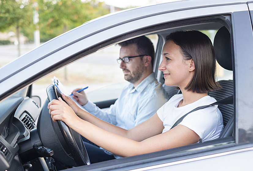 Kobieta kursantka oraz mężczyzna instruktor w samochodzie.