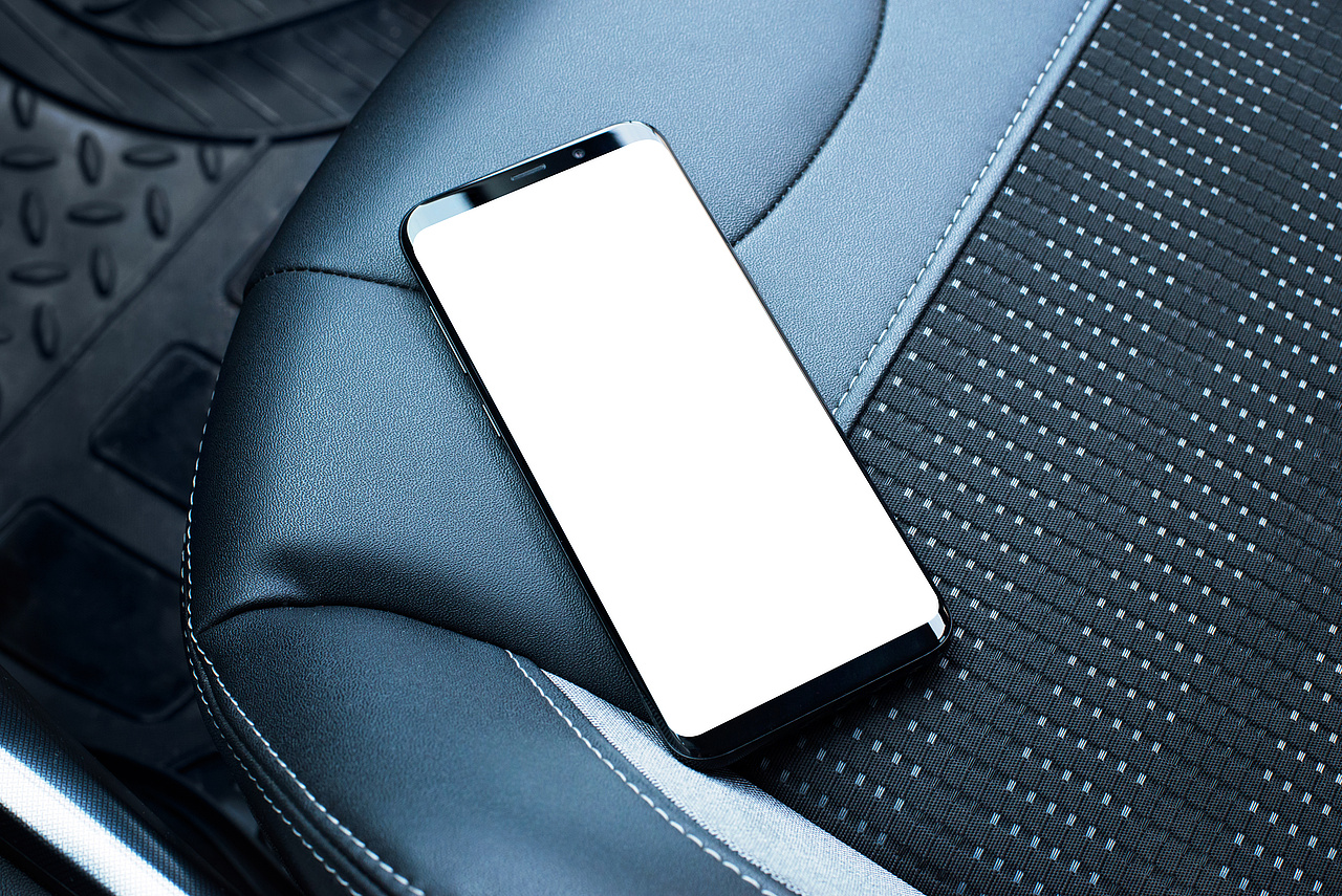 Smartfon leżący na fotelu samochodowym.