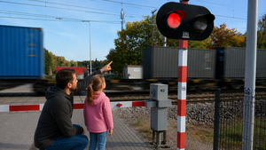 Mężczyzna z dziewczynką wskazuje na sygnalizator na przejeździe