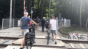 Rowerzyści przechodzacy przez przejście przez tory.