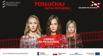 Billbord kampanii, tekst Uważaj na przejeździe kochanie, w centrum - postacie 2 kobiet i dziewczynki.