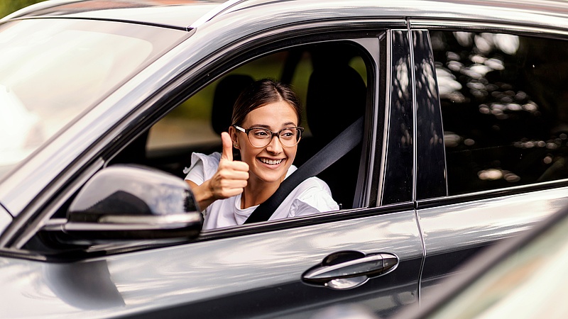 Kobieta za kierownicą samochodu pokazująca gest uniesionego kciuka