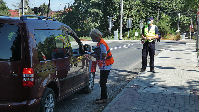 Koordynator wręcza ulotkę kierowcy, na drugim planie funkcjonariusz SOK