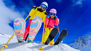 Zdjęcie od dołu, dwójka młodych narciarzy.